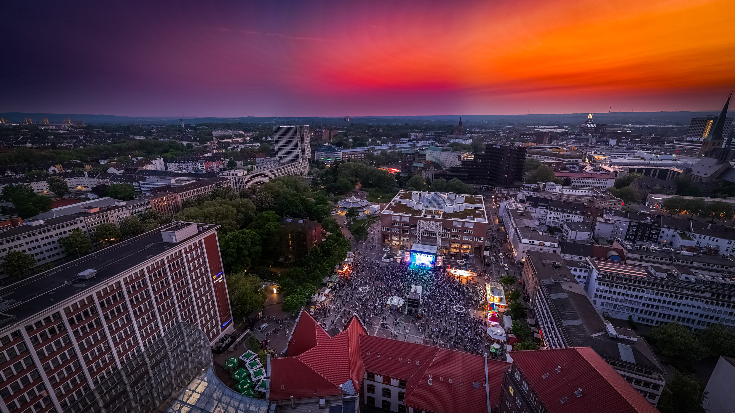 Luftbild vom Friedensplatz Dortmund bei Sonnenuntergang und mit Publikum vor der Dortbunt-Bühne.