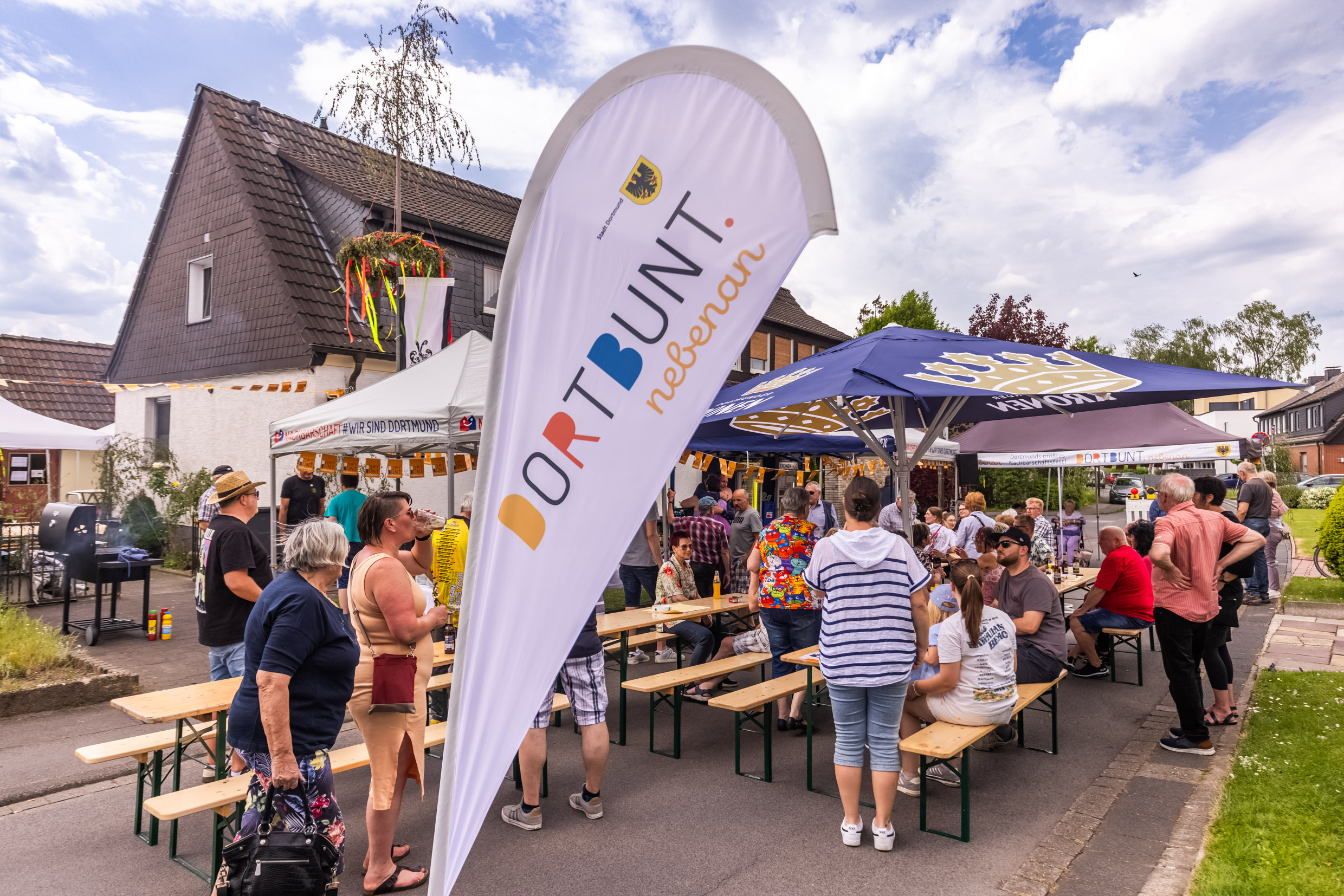 Menschen vor Bierzeltgarnituren beim Nachbarschaftsfest in Mengede.