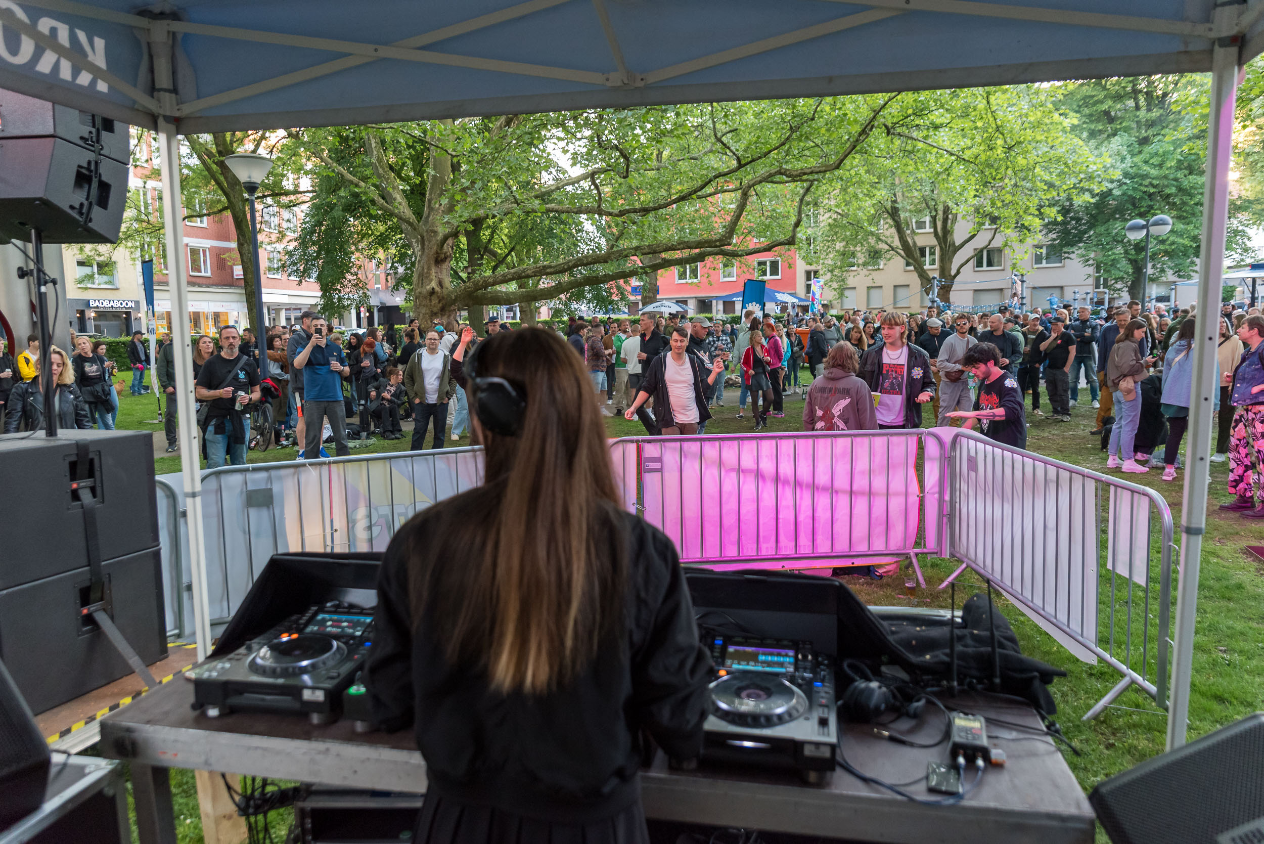 Eine Frau von hinten am DJ-Pult, im Hintergrund eine Menschenmenge.